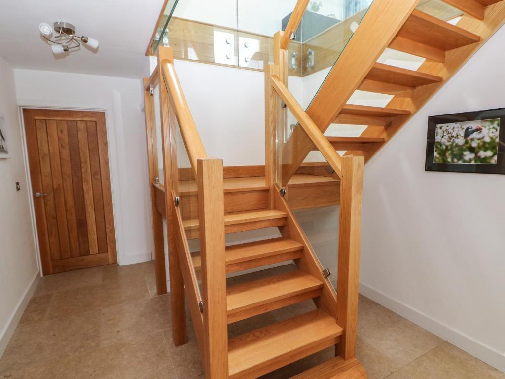 a wooden spiral staircase with glass railing in a house at Gwelfor, Marloes in Haverfordwest