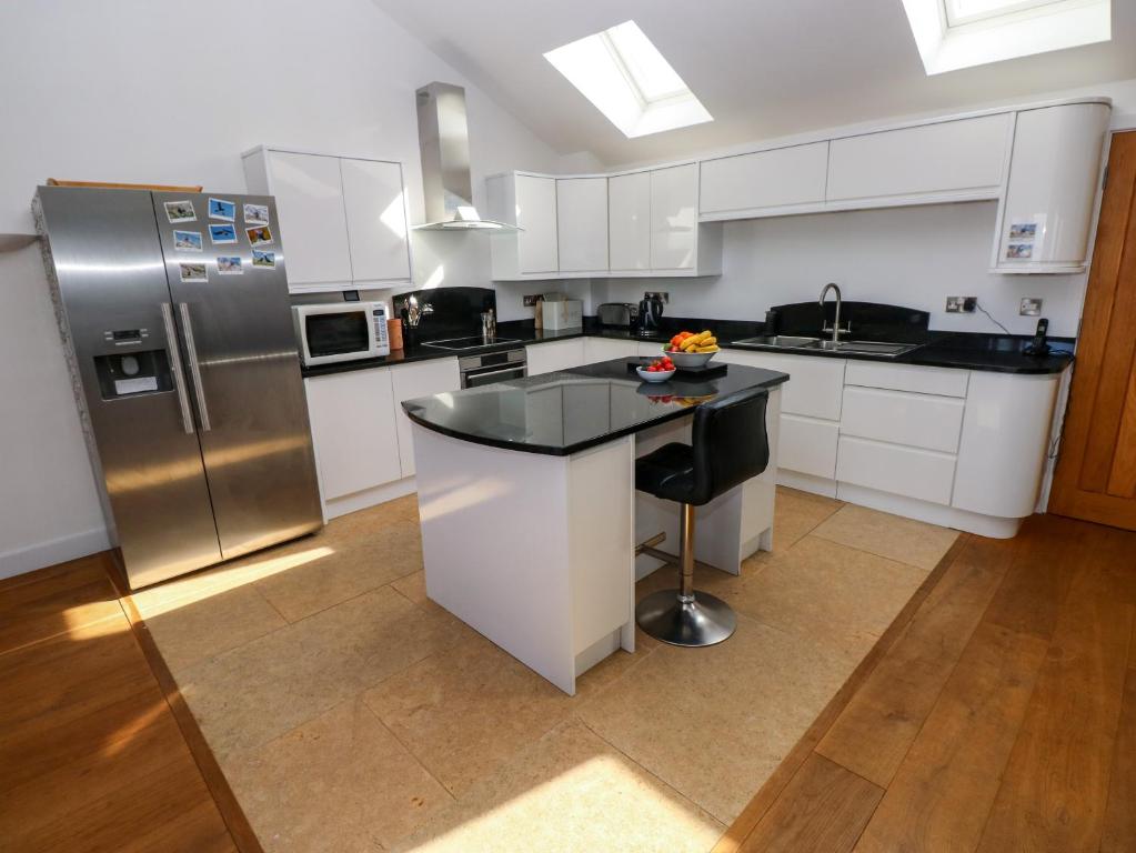 a kitchen with white cabinets and stainless steel appliances at Gwelfor, Marloes in Haverfordwest