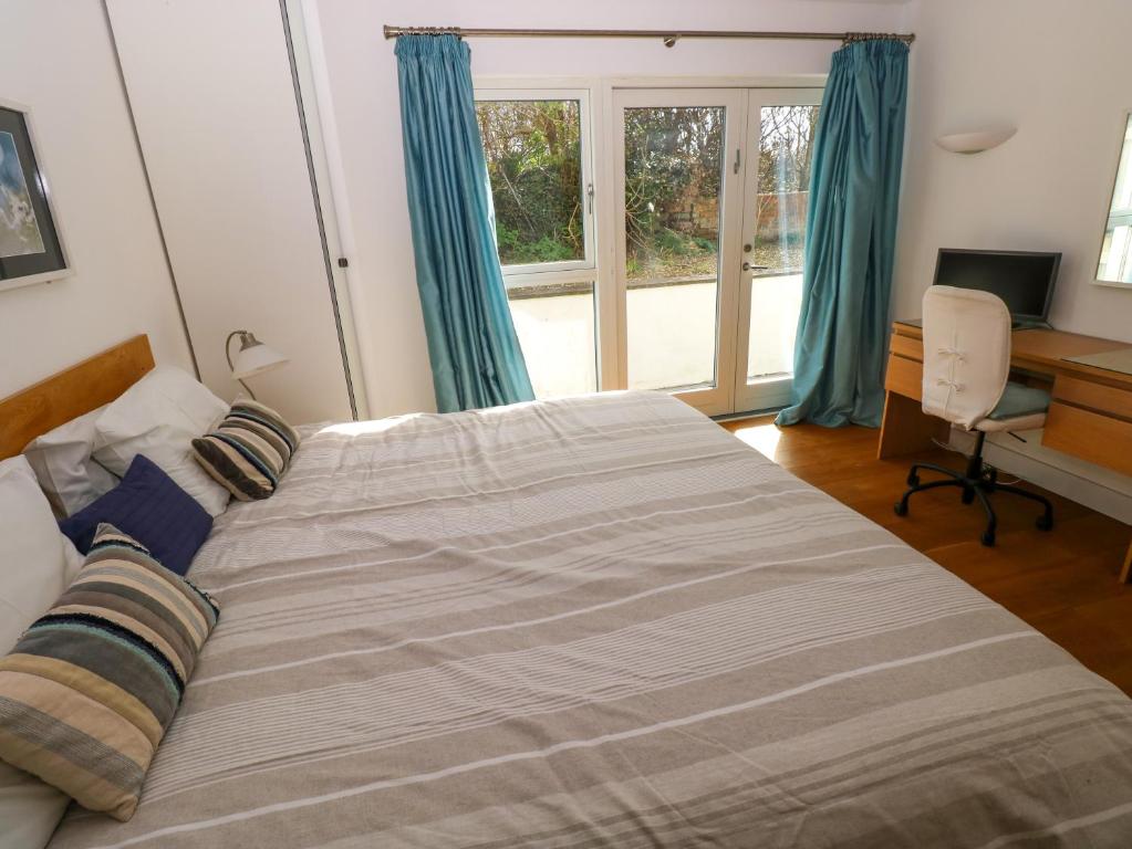 a bedroom with a bed and a desk and a window at Gwelfor, Marloes in Haverfordwest