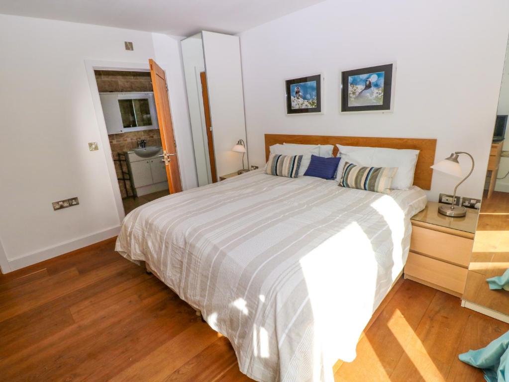 a bedroom with a large bed and a wooden floor at Gwelfor, Marloes in Haverfordwest