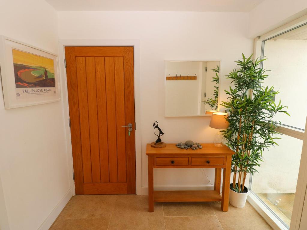 a hallway with a wooden door and a table with plants at Gwelfor, Marloes in Haverfordwest