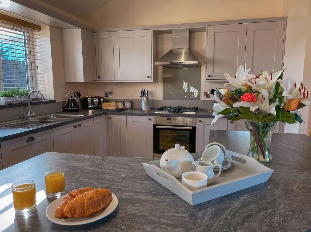 a kitchen with a table with a plate of bread and flowers at Pwyll Holiday Cottage in Pentraeth