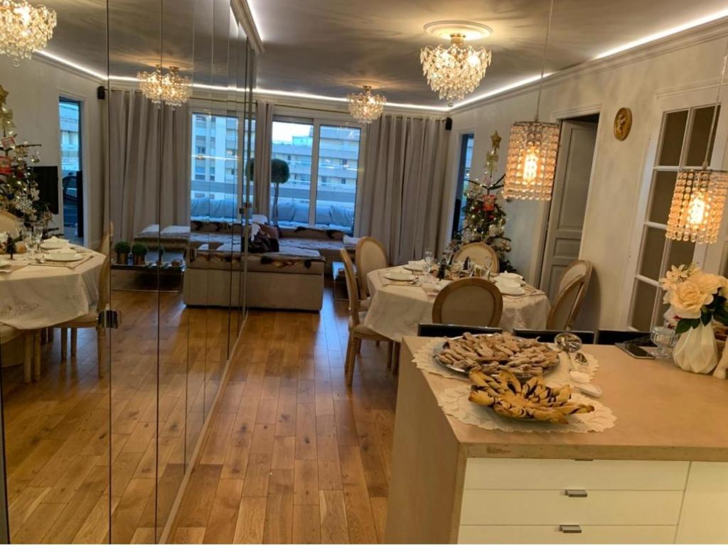 un salon avec des tables et des chaises ainsi qu'une salle à manger dans l'établissement Appartement Belle Feuille, à Boulogne-Billancourt