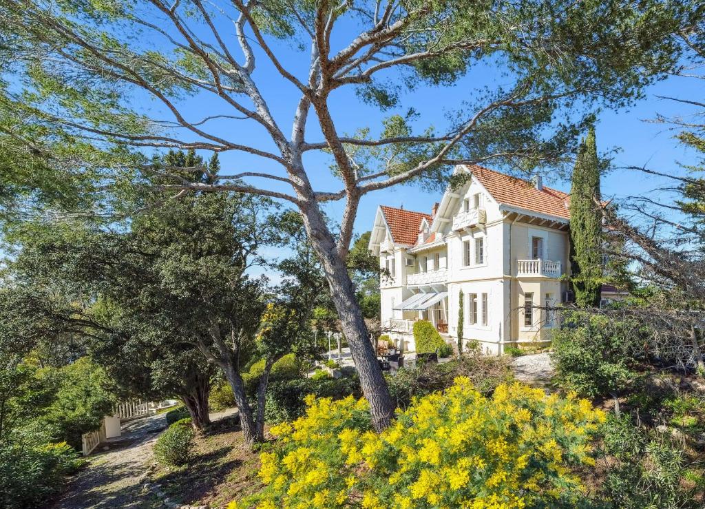 une grande maison blanche avec des arbres et des fleurs dans l'établissement Villa Saint-Raphael, à Saint-Raphaël
