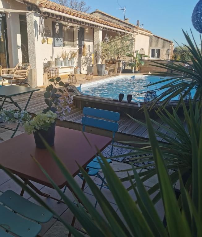 une piscine avec des chaises bleues et une maison dans l'établissement Villa exotique, à Paulhan