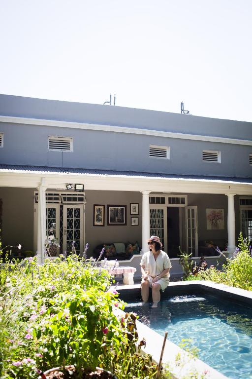 a woman sitting in front of a house with a pool at Afrika-Pearl in Paarl