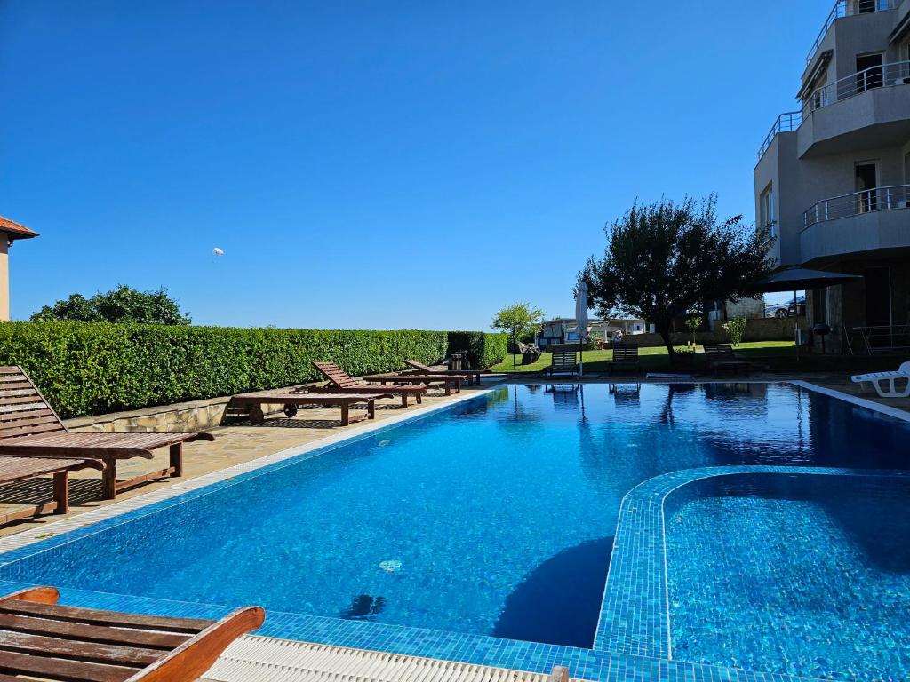 Una gran piscina con sillas y un edificio. en High in the Sky Apartments, en Sozopol