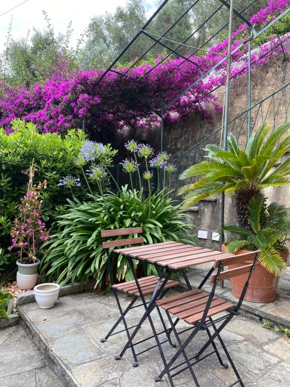 een tafel en een stoel in een tuin met bloemen bij casa lella home in Recco