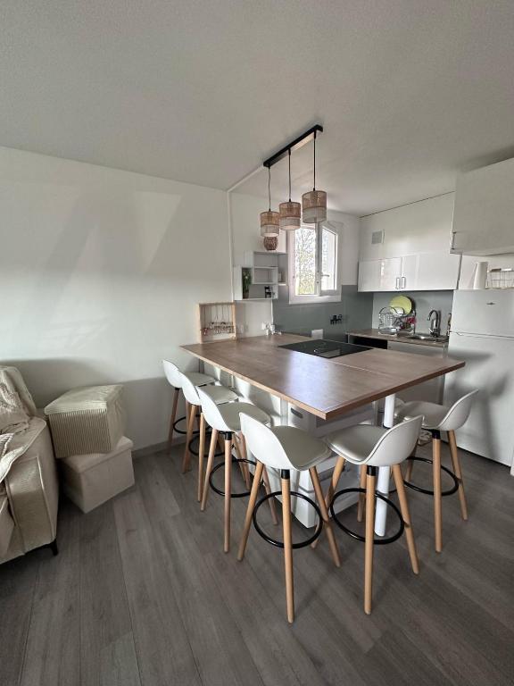 une cuisine avec une grande table et des chaises en bois dans l'établissement Appartement 2 chambres cosy, à La Grande Motte