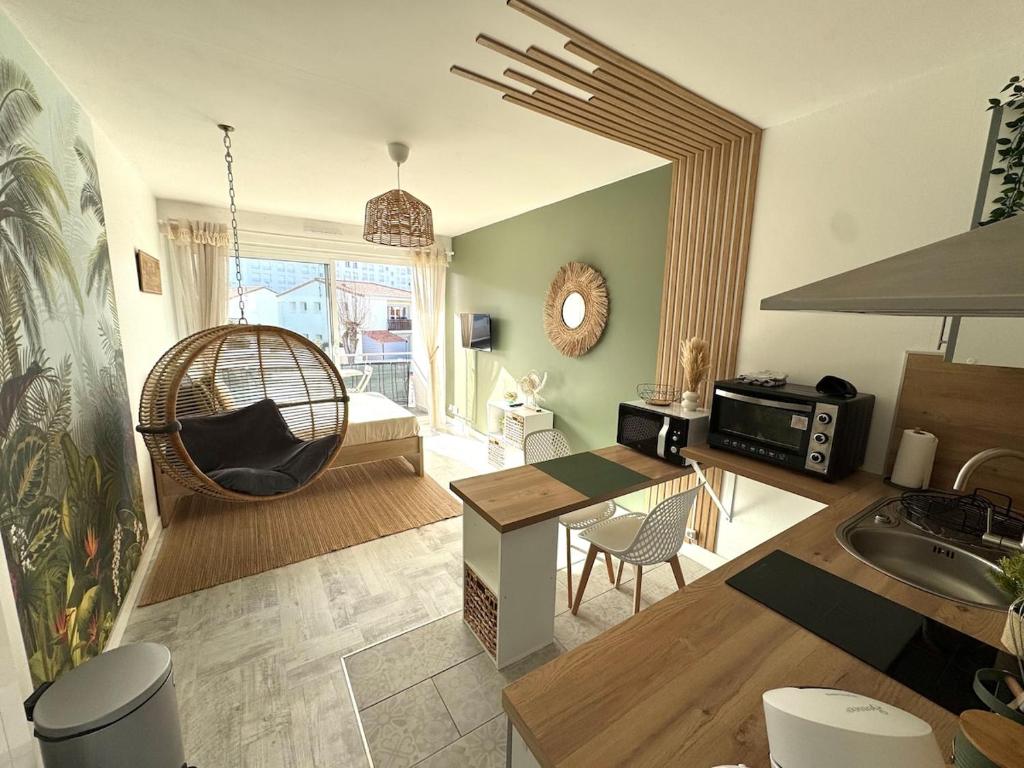 - un salon avec une table et une balançoire dans l'établissement Rêve Tropical, Proche plage, place de parking, à Saint-Jean-de-Monts