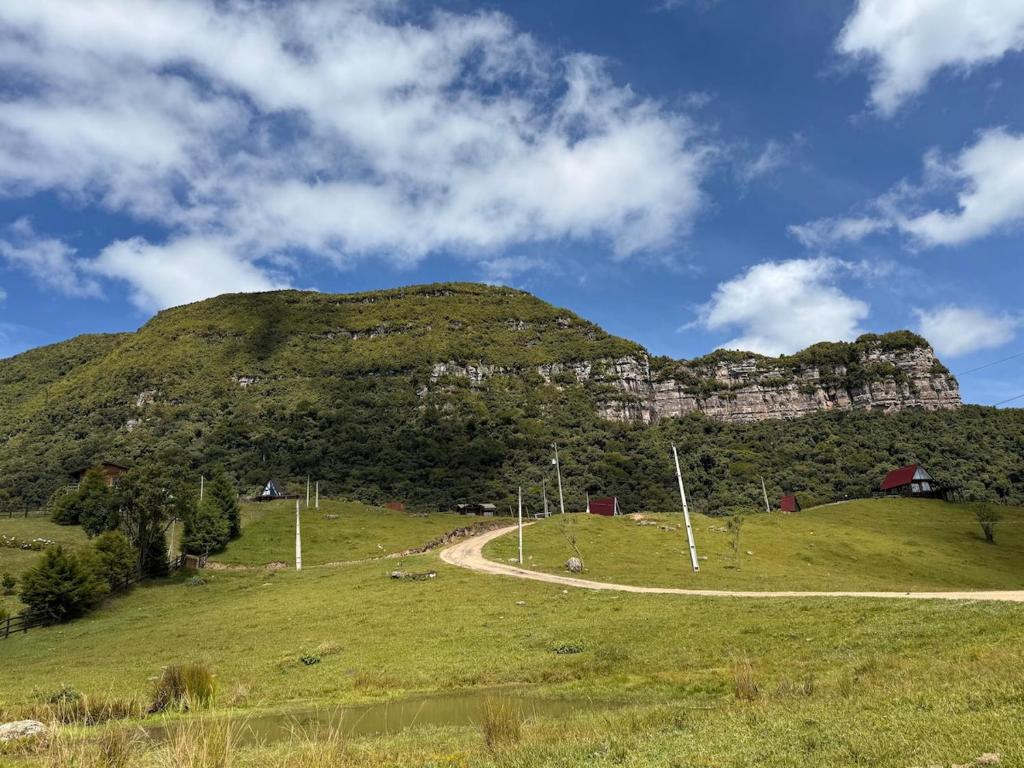 a mountain with a winding road on a grassy hill at Cabana Jardim Encantado in Barracão