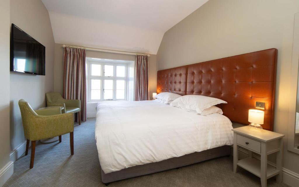 a bedroom with a large bed and a desk and a television at Heacham Manor Hotel in Hunstanton
