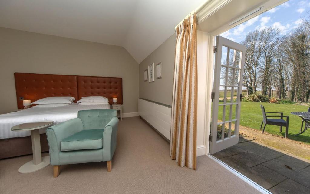 a bedroom with a bed and a chair and a window at Heacham Manor Hotel in Hunstanton
