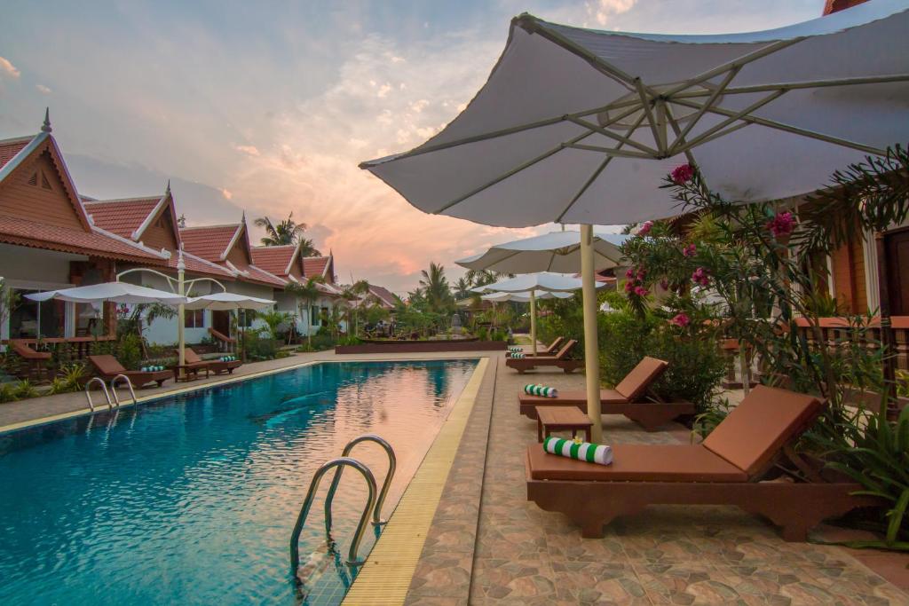 a pool with chairs and an umbrella next to a resort at RaVorn Villa Boutique in Battambang