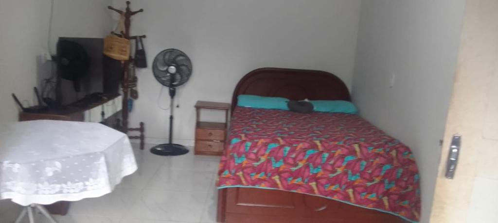 a bedroom with a bed with a blanket and a table at Lar YAMAGUCHI COP 30 in Belém