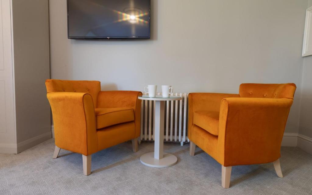 two orange chairs and a table with a tv at Heacham Manor Hotel in Hunstanton