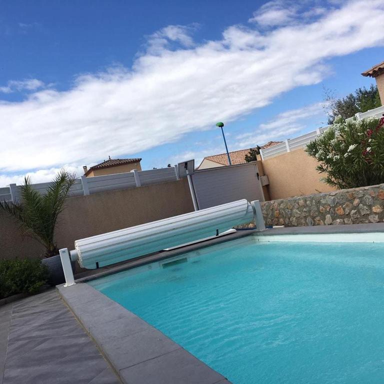 - une piscine avec banc à côté d'un bâtiment dans l'établissement Saint Cyprien Jolie villa climatisee avec piscine et jardin, à Saint-Cyprien