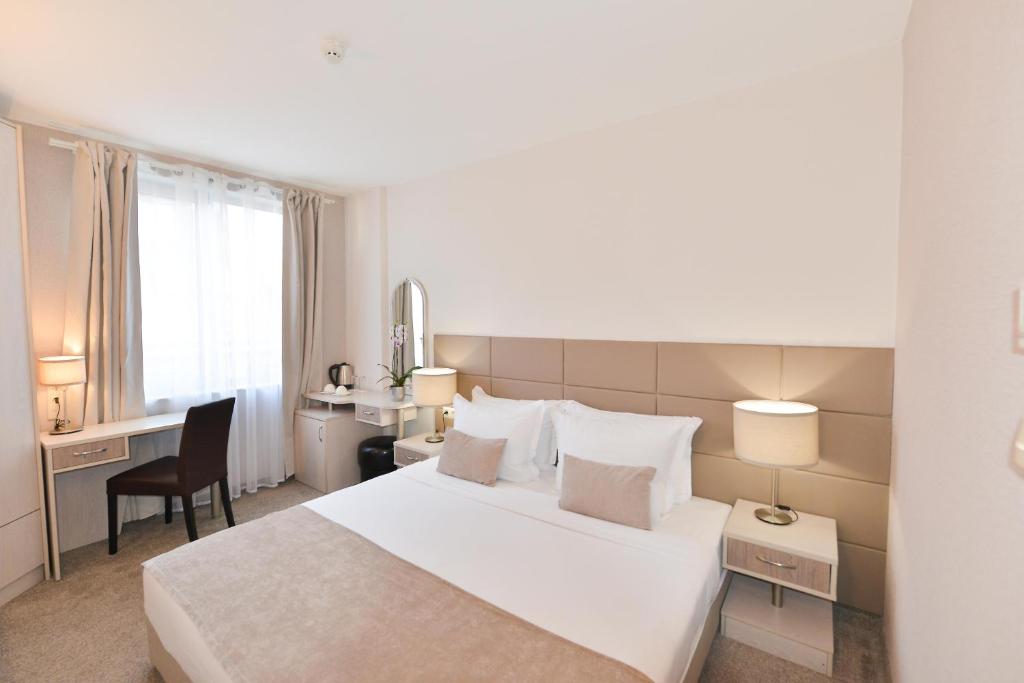 a hotel room with a large white bed and a desk at Art Plaza Hotel in Sofia
