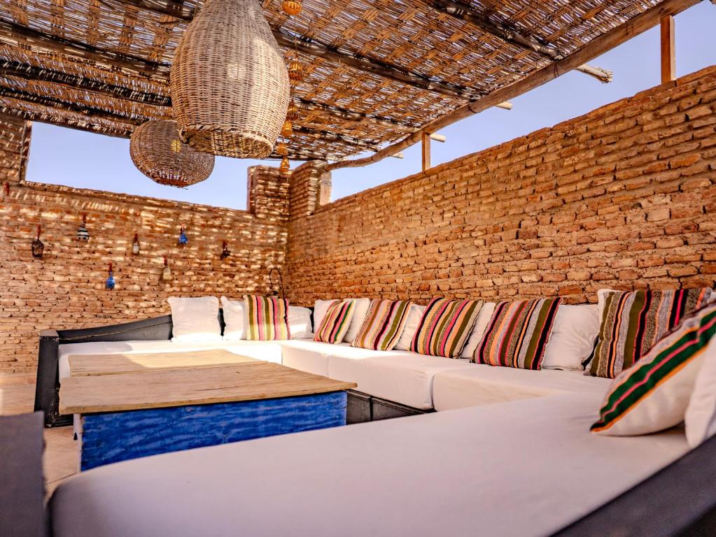 Cette chambre dispose de canapés blancs et d'un mur en briques. dans l'établissement Riad Mayan & Spa, à Marrakech