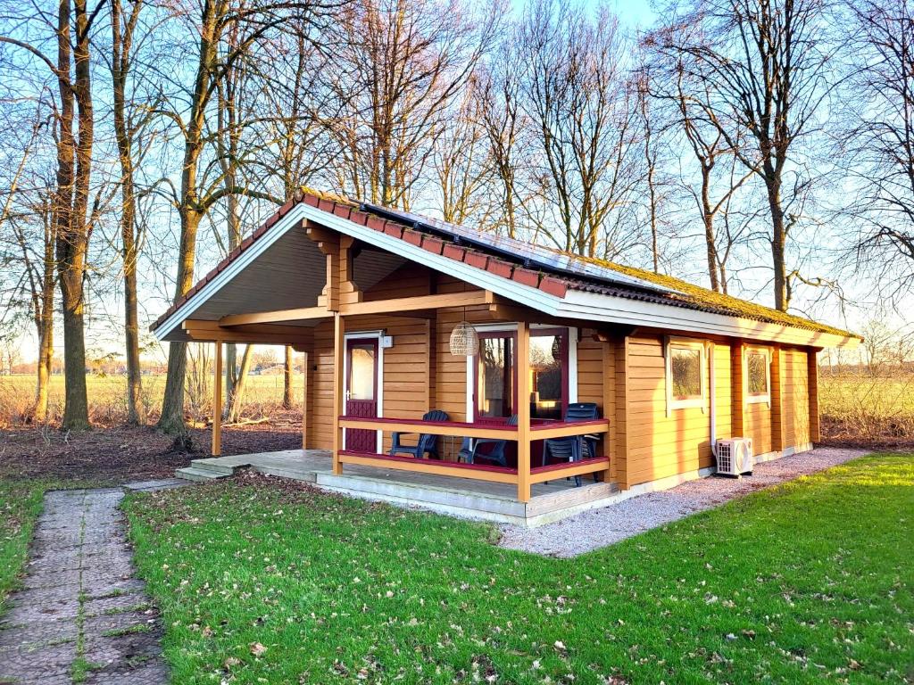 a small wooden cabin in the middle of a field at Hip Huisje van Hout in Gramsbergen