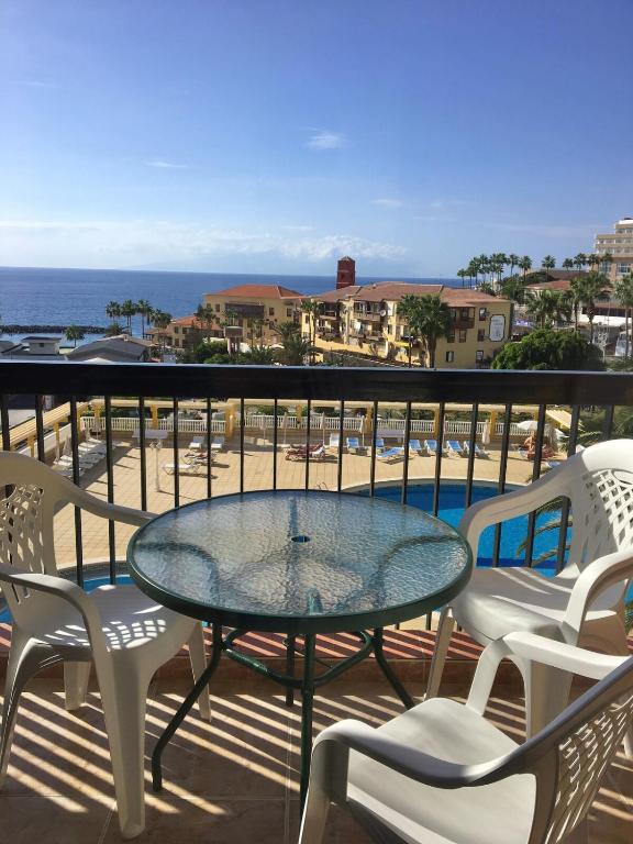 a patio with a glass table and chairs on a balcony at Copacobana Ocean View Playa Las Americas in Costa de Adeje