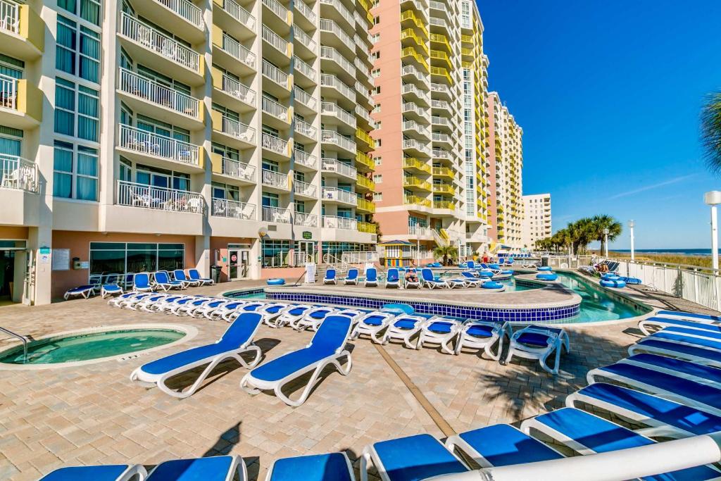 a resort with chairs and a swimming pool and a building at Oceanfront TOP LOCATION MODERN RESORT Lazy River Huge Pool Oasis in Myrtle Beach