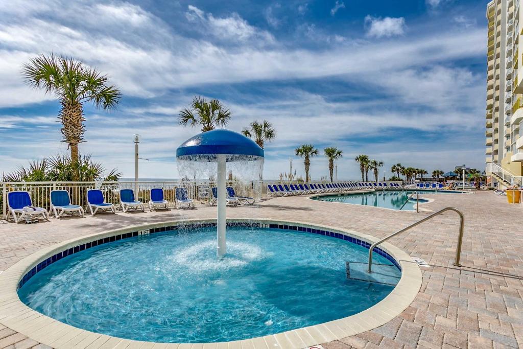 a pool with an umbrella and chairs and palm trees at Oceanfront TOP LOCATION MODERN RESORT Lazy River Huge Pool Oasis in Myrtle Beach