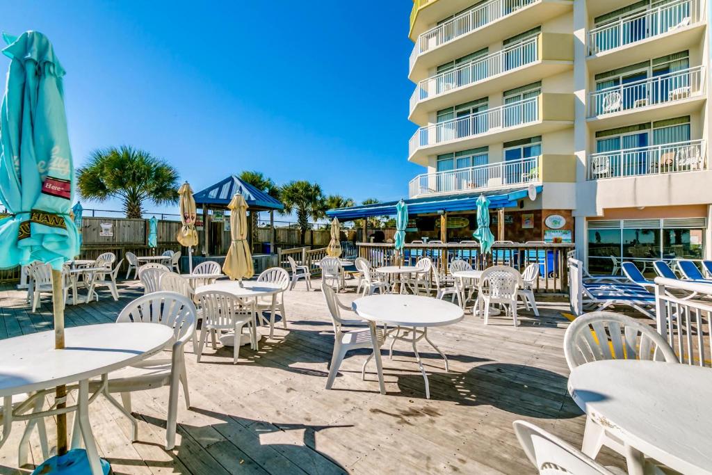 a patio with tables and chairs in front of a hotel at Oceanfront TOP LOCATION MODERN RESORT Lazy River Huge Pool Oasis in Myrtle Beach