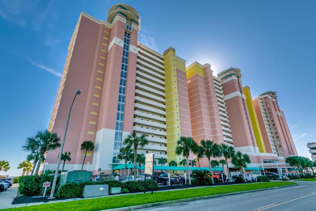a large building with palm trees in front of a street at Oceanfront TOP LOCATION MODERN RESORT Lazy River Huge Pool Oasis in Myrtle Beach