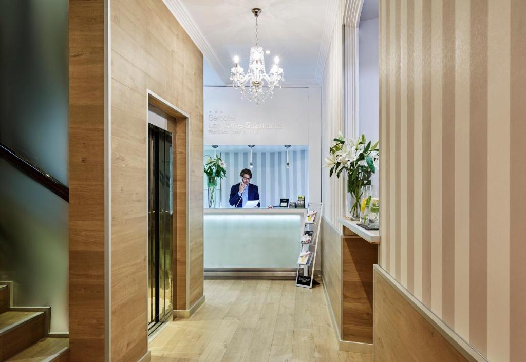 a man is standing at a counter in a hallway at Sercotel Las Torres in Salamanca