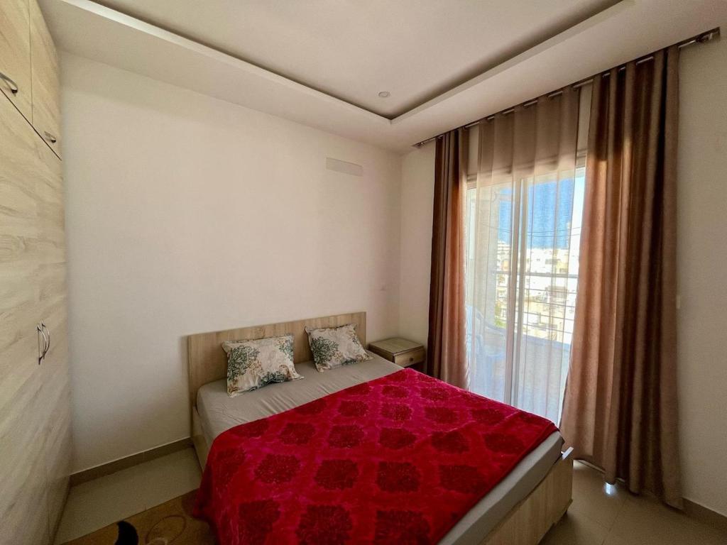 a bedroom with a bed with a red comforter and a window at Sousse Charm, Beach & History in Sousse