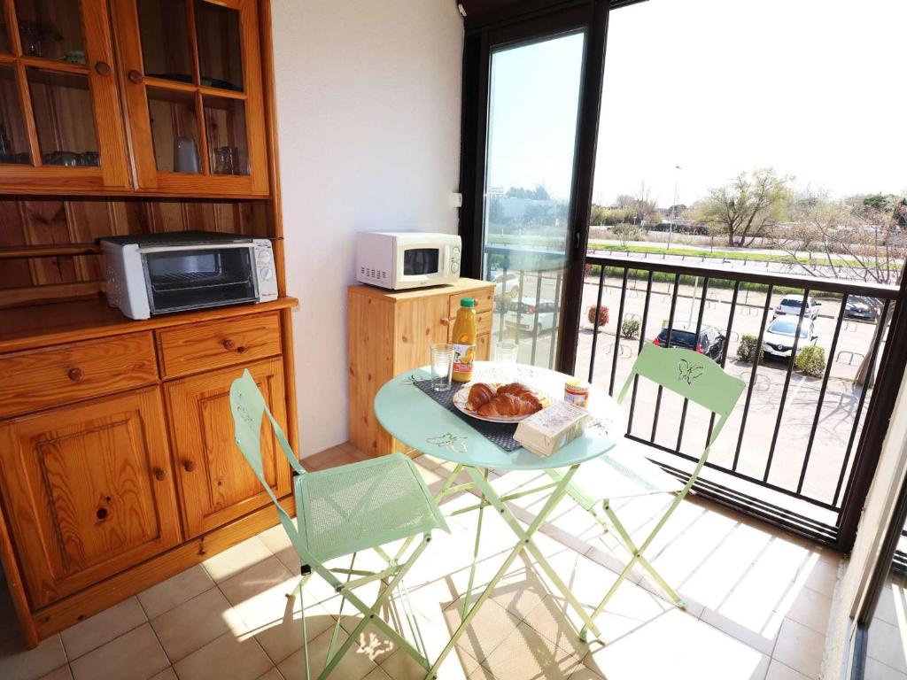 Il dispose d'un balcon et d'une cuisine avec une table et des chaises. dans l'établissement Spacieux 2 pièces avec piscine, ascenseur, proche mer et commerces - FR-1-307-213, au Grau-du-Roi