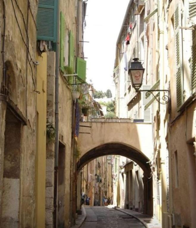 une allée avec une arche entre deux bâtiments dans l'établissement Vieille ville Menton, à Menton