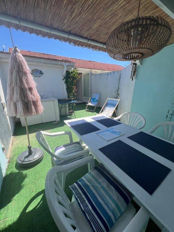 une terrasse avec une table, des chaises et un parasol dans l'établissement APPART BISCA plage, à Biscarrosse