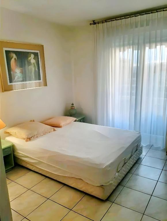 une chambre avec un grand lit blanc et une fenêtre dans l'établissement Le Loft, à Cannes