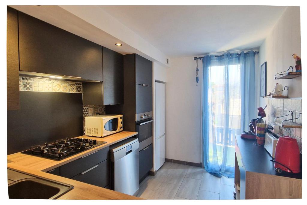 une cuisine avec une cuisinière et un micro-ondes dans l'établissement L'Iranget, maison de vacances 6 pers à 100 mètres des plages de Valras-Plage, à Valras-Plage