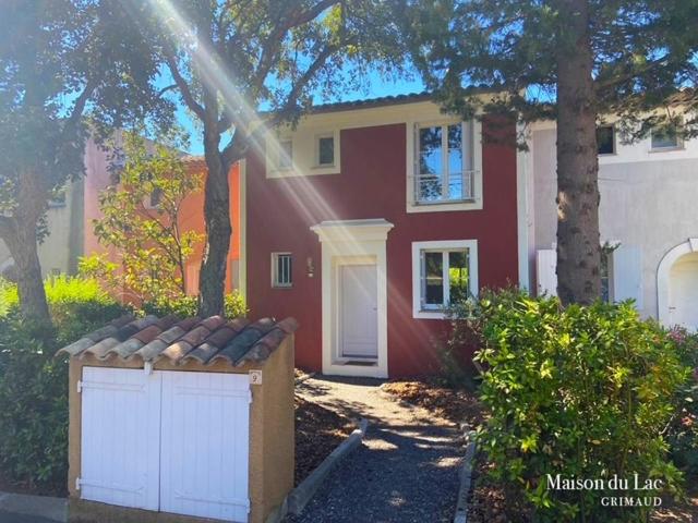 a red house with a white garage in front of it at Maison du Lac in Grimaud