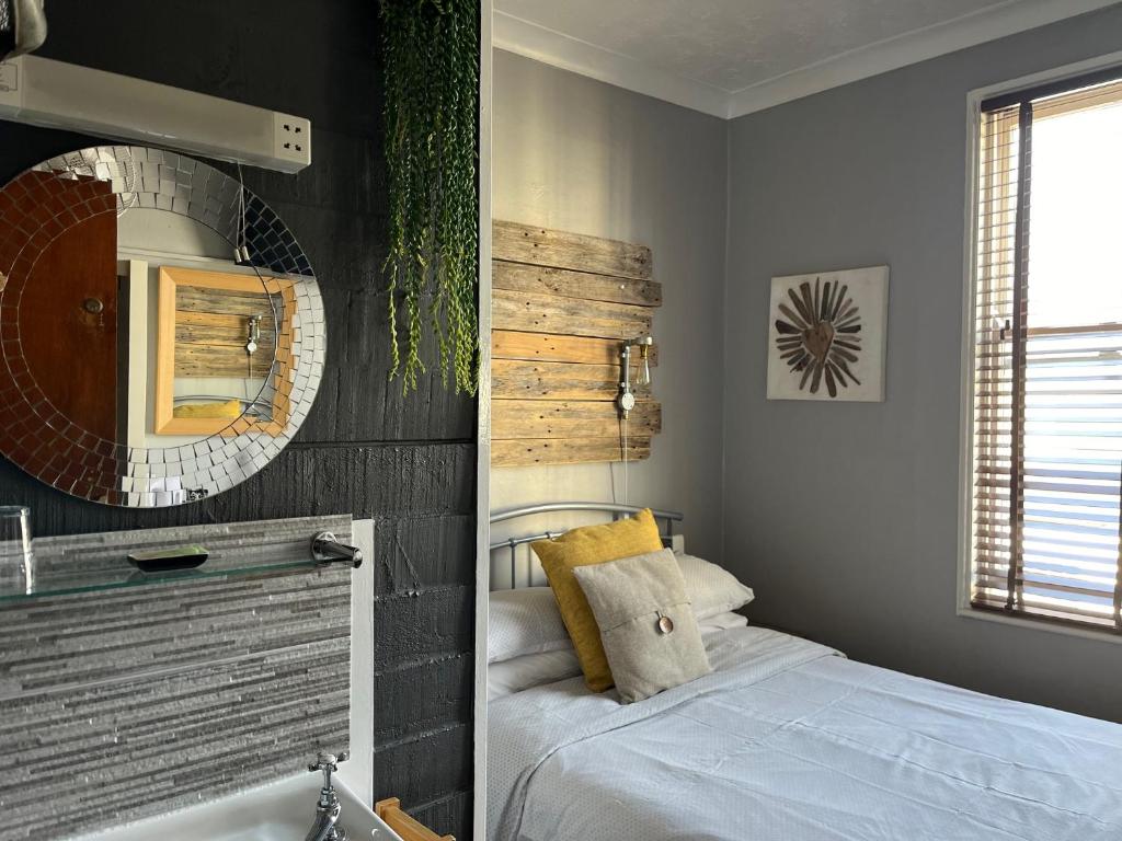 a bedroom with a bed and a mirror and a tub at Kelston Guest House in Weymouth
