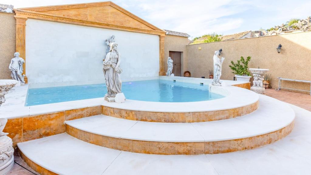 a large pool in a courtyard with statues at La Fuente Romana Priego de Córdoba by Ruralidays in Priego de Córdoba