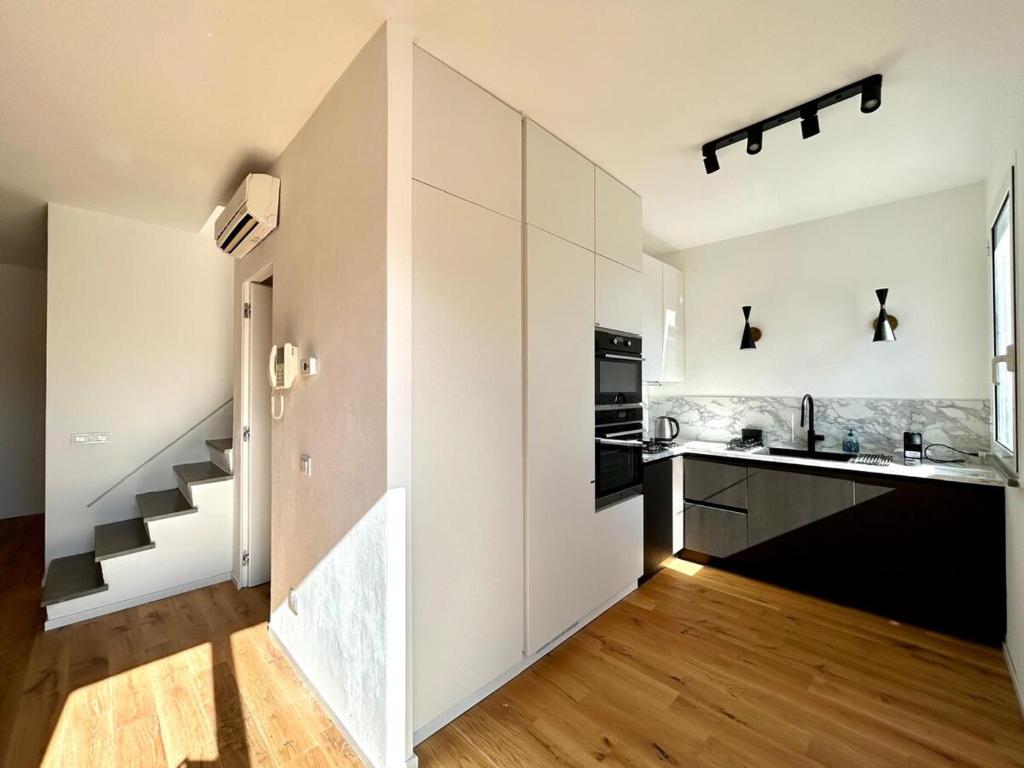 a kitchen with white walls and wooden floors and a staircase at Casa Sarina Modern apartment with city and sea view up to 6 ppl garage on request in La Spezia