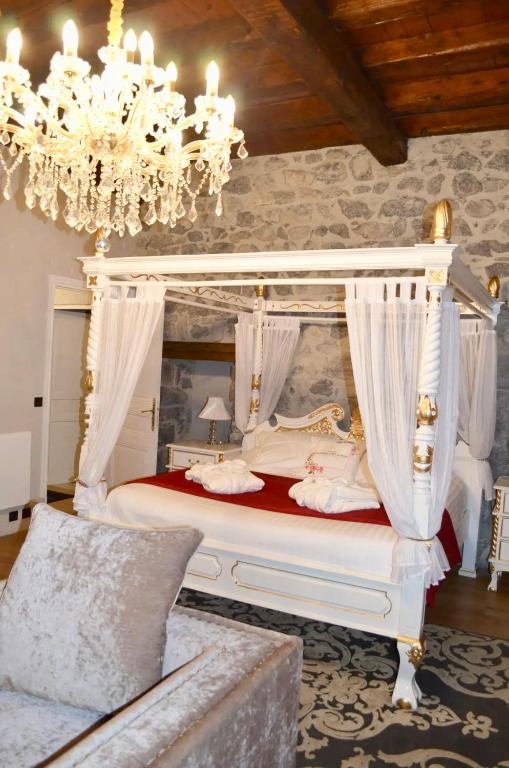- une chambre avec un lit à baldaquin et un lustre dans l'établissement Château de la Rive - Suite Prestige - Chambre 2 personnes, à Cruet