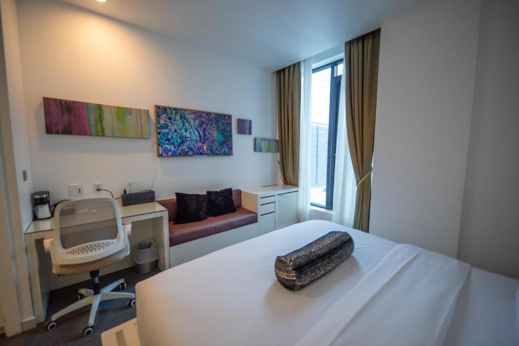 een slaapkamer met een bed, een bureau en een stoel bij The One Boutique Hotel in Queens