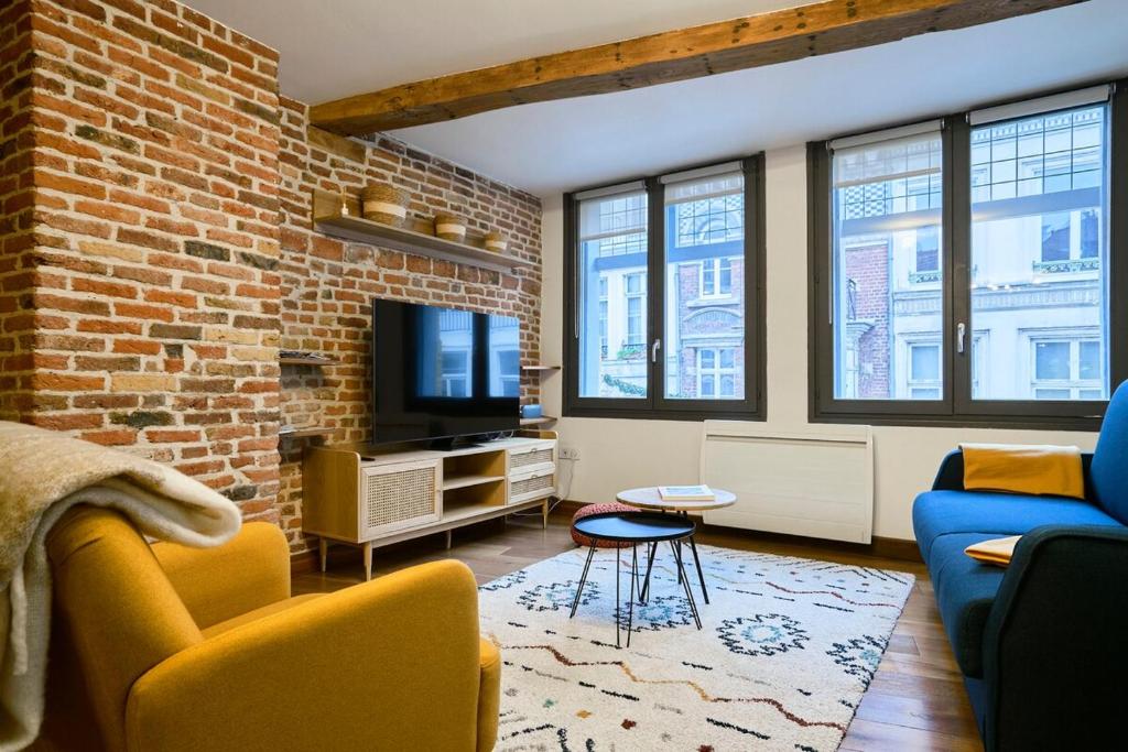 un soggiorno con un muro di mattoni e una TV di Duplex Rue Royale, rooftop, balnéo spa a Lille