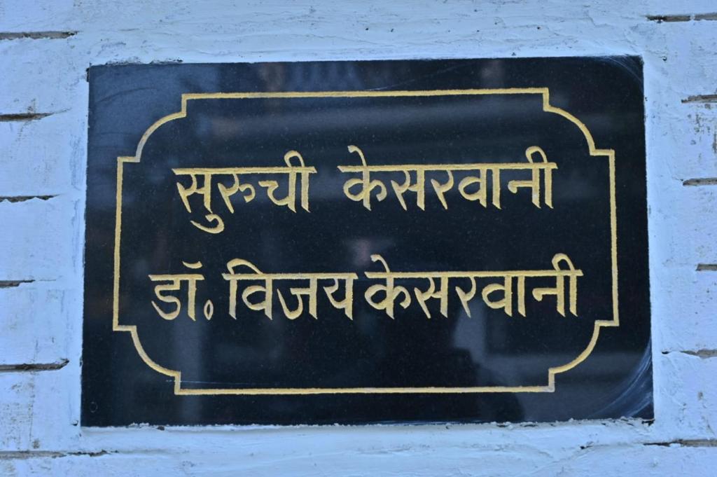 una señal en una pared de ladrillo con escritura en ella en Jai Villa homestay, en Prayagraj