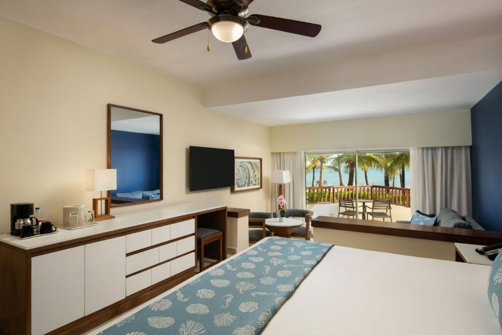 a bedroom with a bed and a desk with a television at Impressive Premium Punta Cana - All Inclusive in Punta Cana