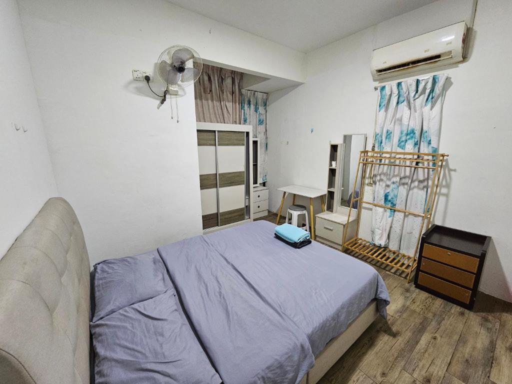 a bedroom with a bed and a table and a window at Sunny Point Hostel in Gelugor