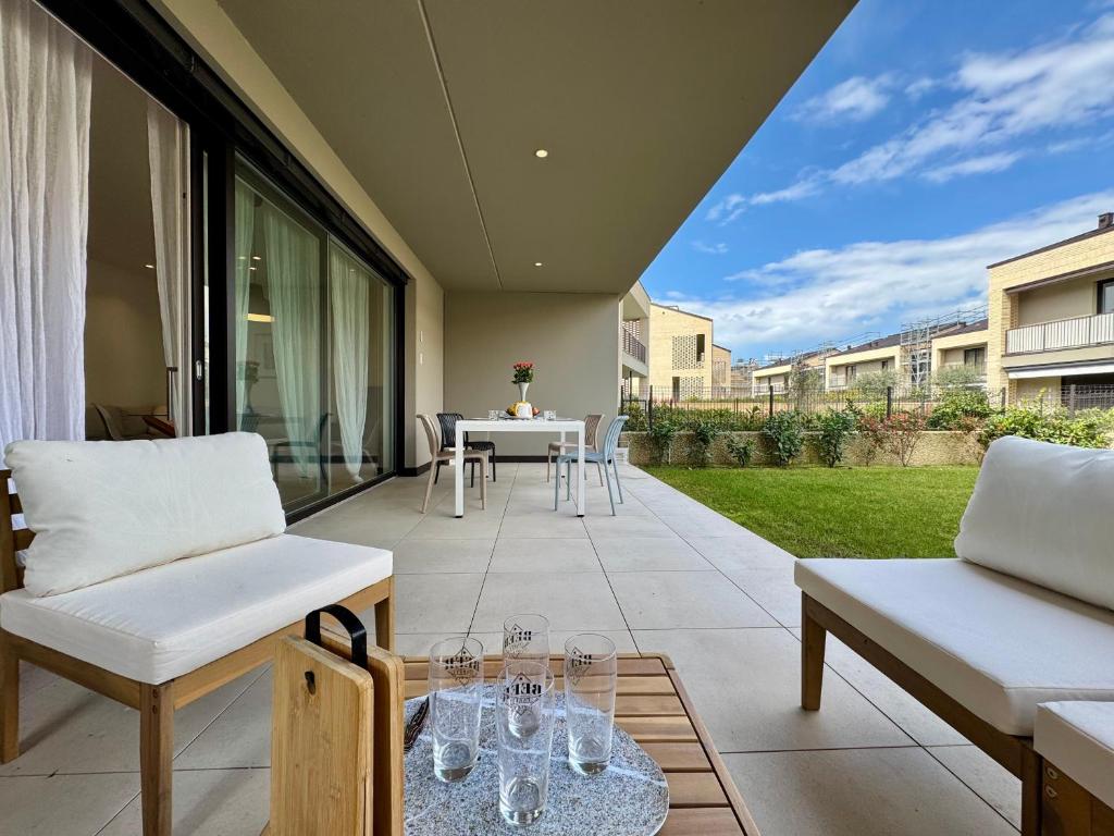 a patio with white chairs and a table with glasses on it at Borgo Garda in Peschiera del Garda