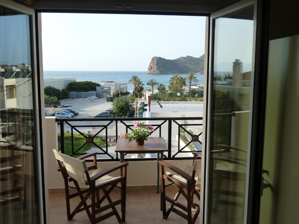 balcón con mesa, sillas y vistas al océano en Mithos Apartments, en Agia Marina de Nea Kydonia