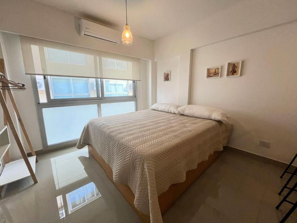 Un dormitorio con una cama y una ventana grande. en Studio en Paseo la Cisterna 712, en Buenos Aires