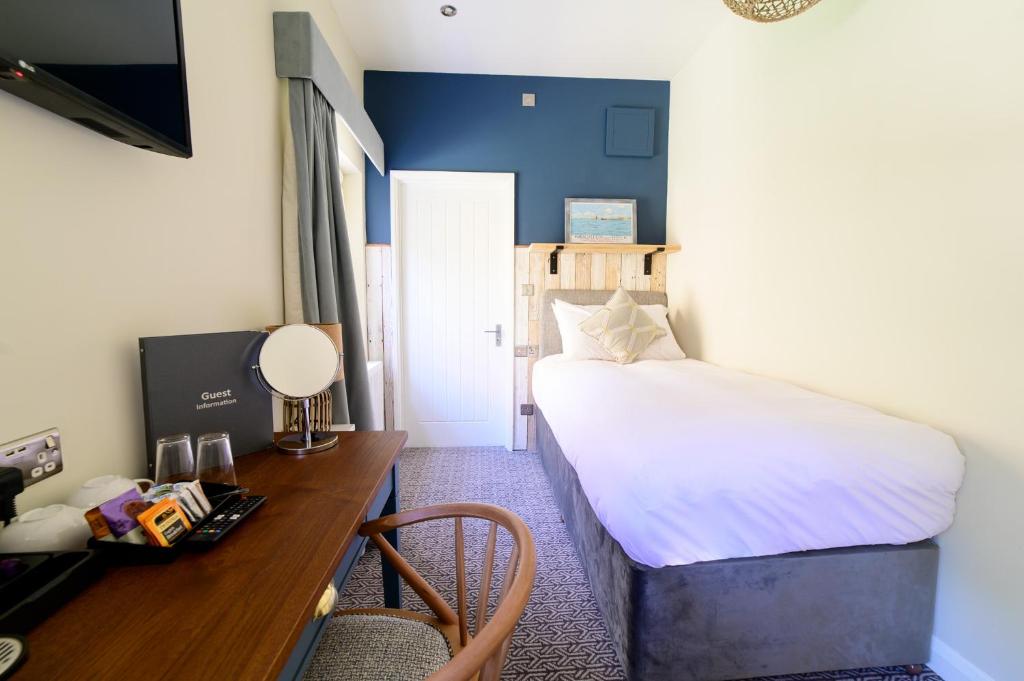 a small room with a bed and a desk with a desk at Downs Hotel in Stanmer